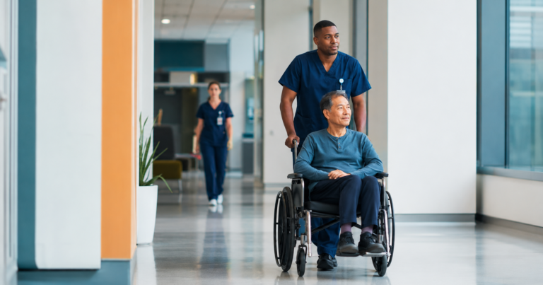 Healthcare patient transporter pushing a patient in a wheelchair